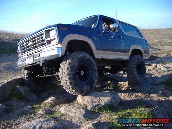 Blue 1986 Ford Bronco with tan trim navigating rocky terrain