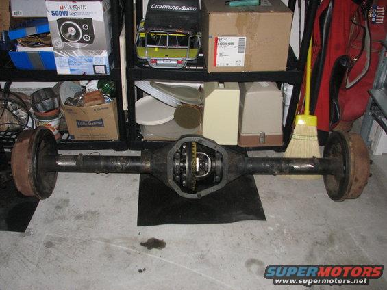 Rear axle assembly with differential exposed, drum brakes on ends, on concrete floor