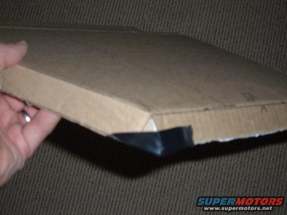 Cardboard box with black plastic trim held by hand