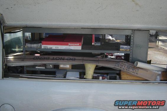 Shelving unit in a truck bed filled with boxes, pipes, and other items. Text on a pipe reads 'DO NOT BEND'