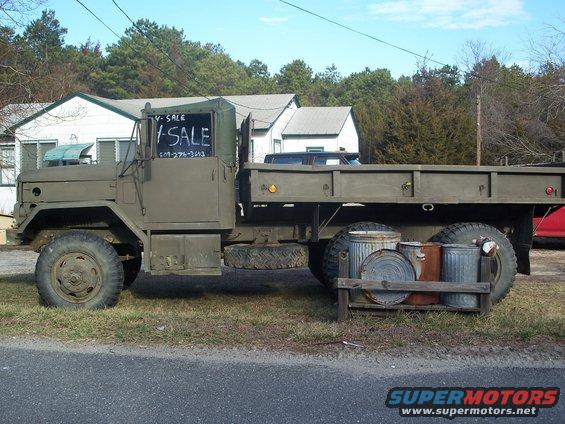 Olive drab military truck side view with "For Sale" sign