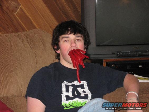 Person with red licorice in mouth sitting on a couch in front of a television