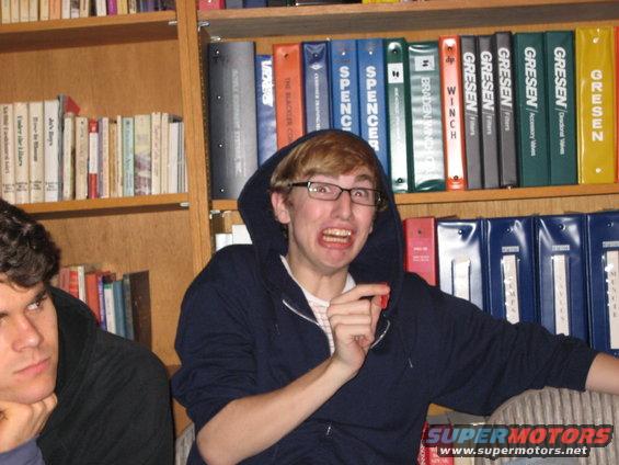 Two people in front of bookshelves; one is making a funny face
