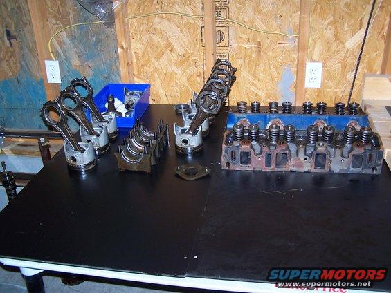 Engine cylinder head and pistons with connecting rods on a black table