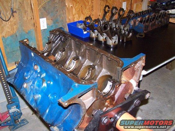 Engine block on stand, with pistons and connecting rods laid out on a table