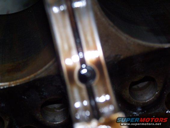 Close-up of a dirty engine connecting rod with oil residue