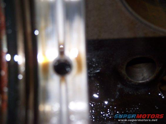 Close-up of a dark, circular engine part with blurry background lights