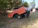 1974 Ford F-100 - An orange truck bed is mounted on a trailer, parked in a yard with trees and outbuildings.