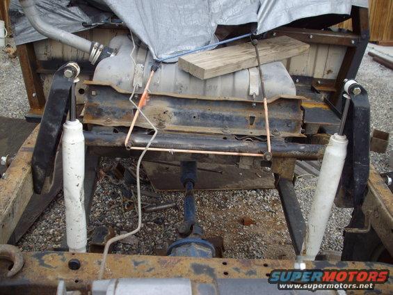 Vehicle chassis with rear suspension components, fuel tank, and exhaust pipe visible