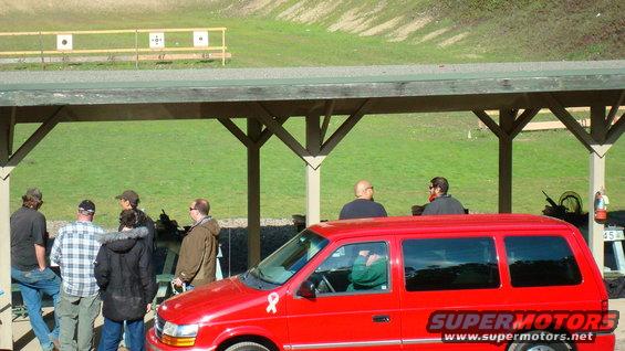 Red minivan parked at a shooting range