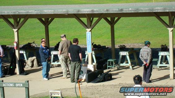 People at a covered shooting range with firearms on tables