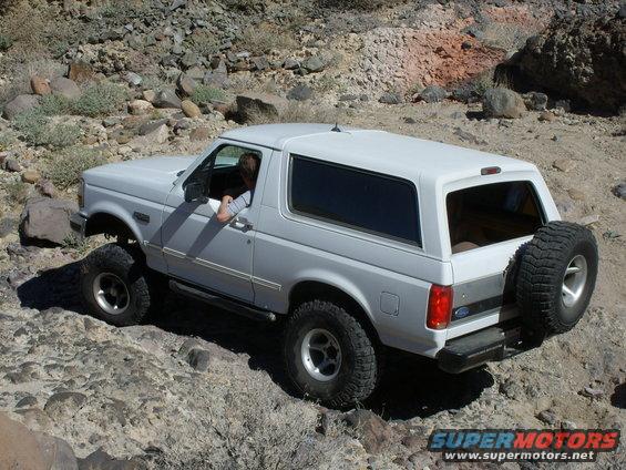 White 1993 Ford Bronco driving on rocky terrain