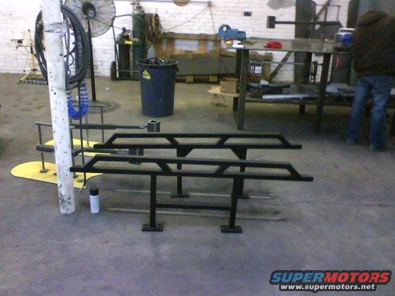 Two black metal rock sliders on a workshop floor