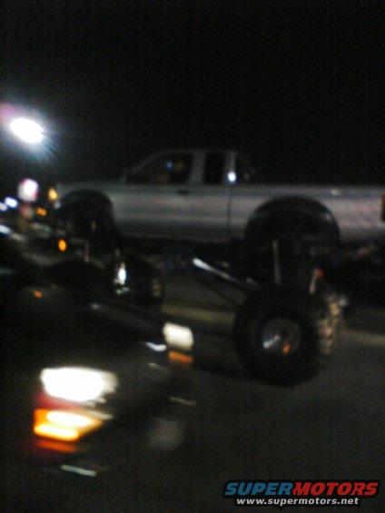 Silver pickup truck with lifted suspension, seen at night