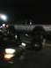2001 Nissan Frontier - A lifted silver pickup truck is visible at night, with another vehicle in the foreground.