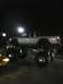 2001 Nissan Frontier - A silver pickup truck is heavily modified with a lift kit and massive tires, seen at night.