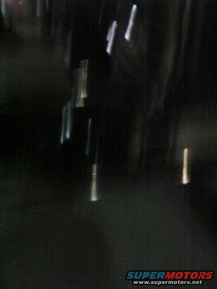Blurry dark scene with vertical light streaks and Supermotors logo