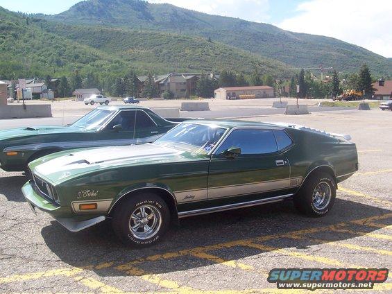green Ford Mustang with silver stripe, parked next to a green Ford Ranchero