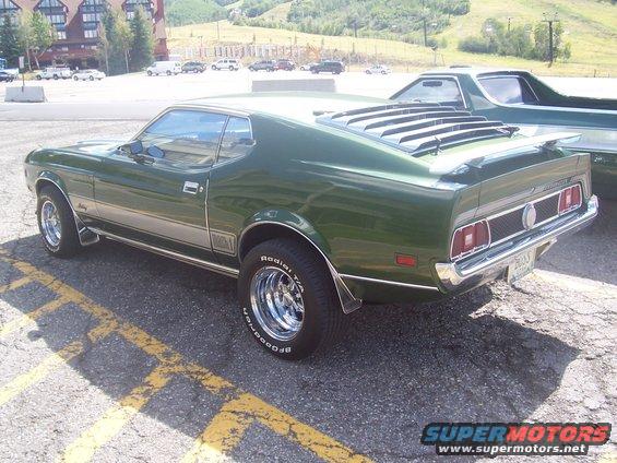 Green 1971 Ford Mustang Mach 1 parked in a lot, rear quarter view. Chrome wheels, louvers on rear window