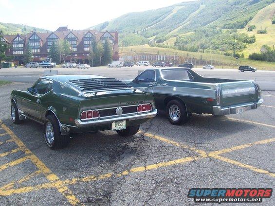 Green 1971 Ford Mustang Mach 1 with louvers and a "BOSS" plate, parked next to a green Ford Ranchero