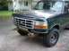 1995 Ford Bronco - Front view of a dark green Ford F-Series truck, showing damage to the bumper and lower front fascia.
