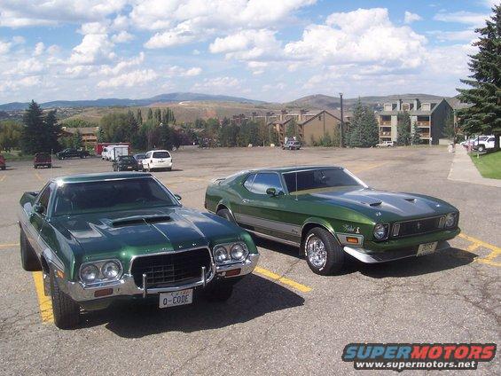 Two green classic cars, a 1971 Ford Mustang Mach 1 and a 1972 Ford Ranchero, parked in a lot