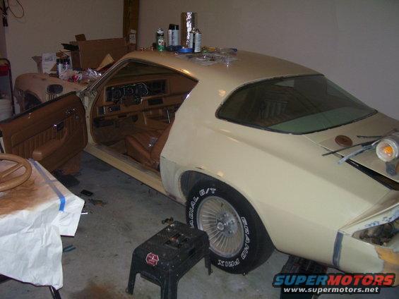 Car in garage, door open, interior visible. Some parts and cans on top