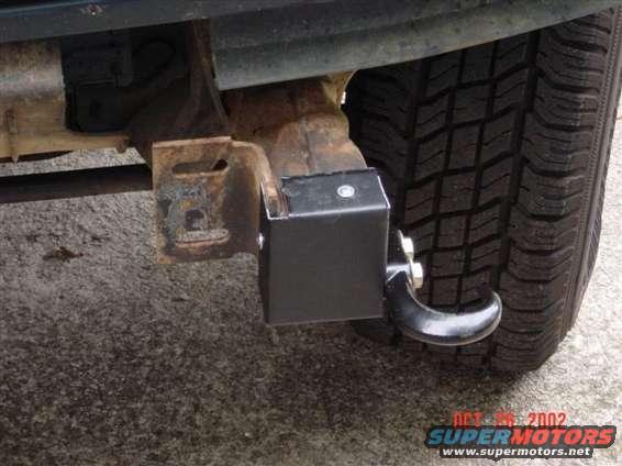 close-up of a tow hitch receiver attached to a vehicle frame near the rear tire