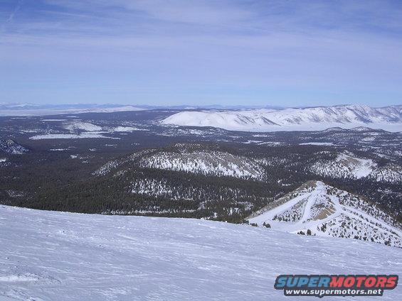 Snowy mountain landscape with trees and a blue sky. Text 'SUPERMOTORS' is visible