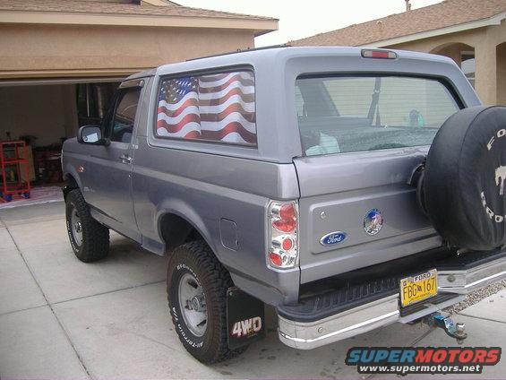 Gray 1995 Ford Bronco, rear quarter view, with spare tire on back and American flag decal on side window