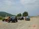 1995 Ford Bronco - A group of off-road vehicles are gathered on a dirt road under a cloudy sky.