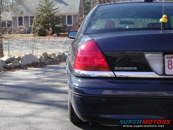 Dark blue sedan rear view, "POLICE INTERCEPTOR" badge visible on trunk lid
