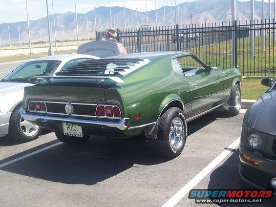 Green 1971 Ford Mustang Mach 1 with louvers on rear window, parked in lot