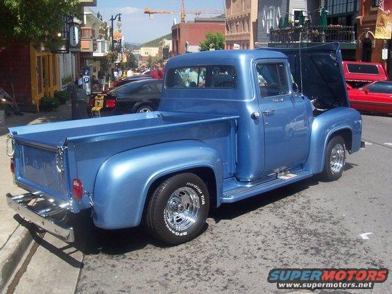Blue pickup truck with hood open, parked on a street