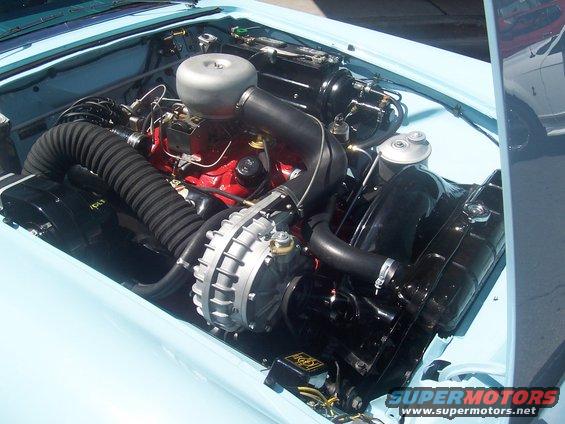 Light blue car engine bay with a red engine block, chrome air cleaner, and black hoses