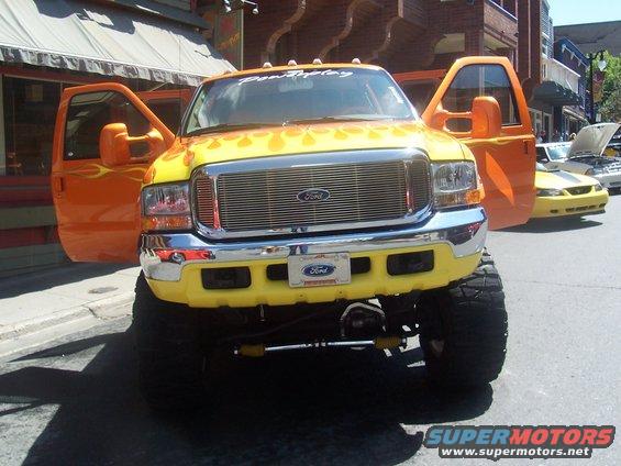 Yellow and orange lifted Ford truck with flame decals and doors open