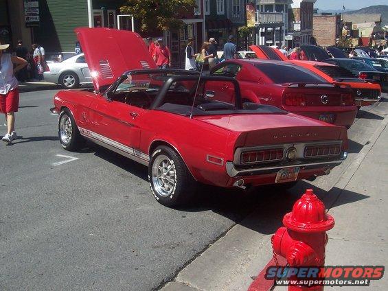 red convertible with Shelby badging parked on street, hood up, other cars behind it