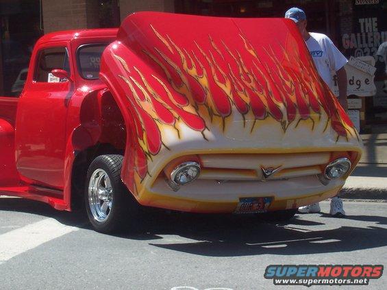 Red pickup truck with flame graphics on the hood, chrome wheels, and a visible license plate