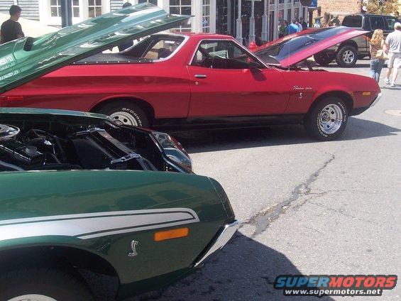 Red Ford Ranchero with hood open, green car in foreground with hood open