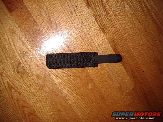 expandable baton with black fabric sheath on wood floor