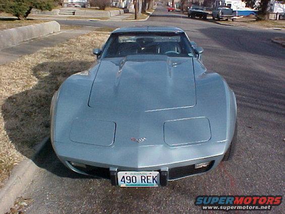 Light blue 1977 Chevrolet Corvette with a hood scoop and pop-up headlights, viewed from the front