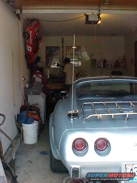 Rear of a light blue 1977 Chevrolet Corvette with dual taillights and a luggage rack