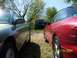 1996 Ford Probe - A red car is parked next to a gray car, with a blue SUV visible in the distance on a sunny day.