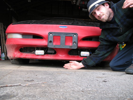 Red 1996 Ford Probe front with a person kneeling beside it