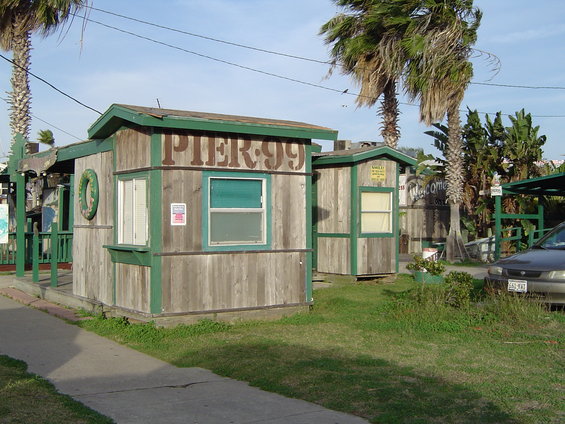 Two wooden buildings with 'PIER 99' signage and a parked car
