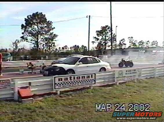 White sedan with black hood on drag strip, side view. Date stamp MAR 24 2002