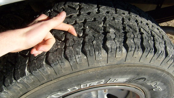 Hand checking the tread depth on a worn tire