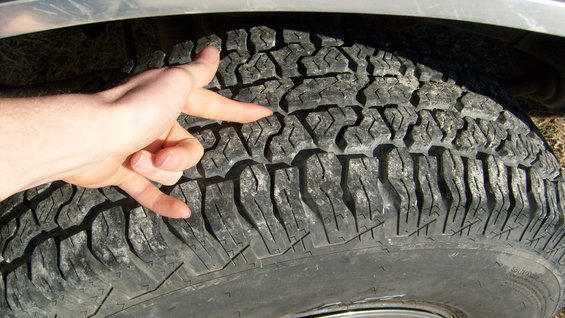 Close-up of a hand measuring the tread depth of an off-road tire