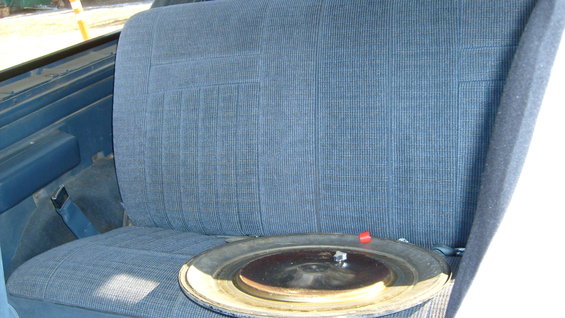 Blue fabric rear seat with a metal hubcap on the cushion