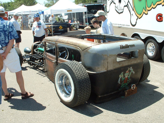 Rat rod car with rusty body, whitewall tires, and 'Bullrun' text on the rear panel